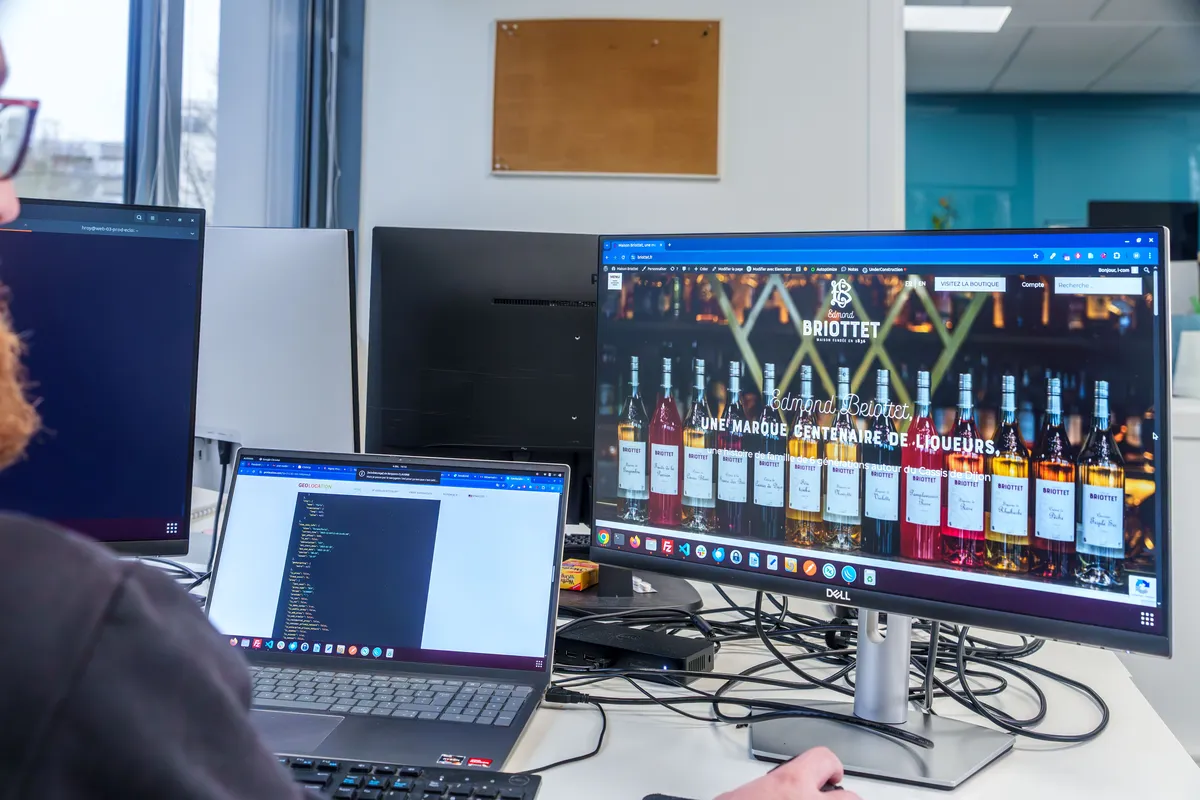 Poste de développement EcloLINK avec code et aperçu d'un site e-commerce client affiché sur plusieurs écrans