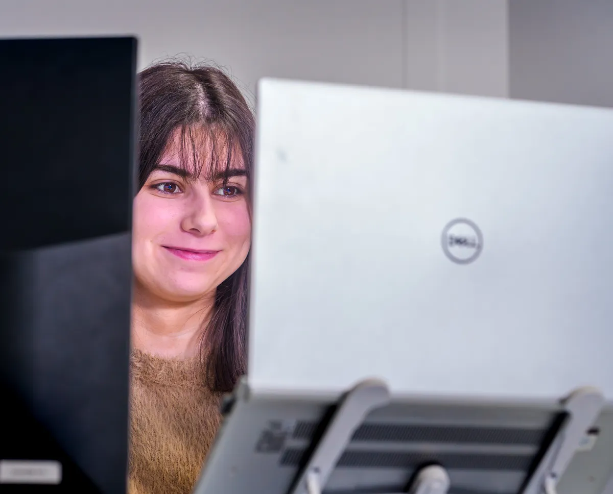 Portrait d’une consultante webmarketing souriante devant son ordinateur portable.