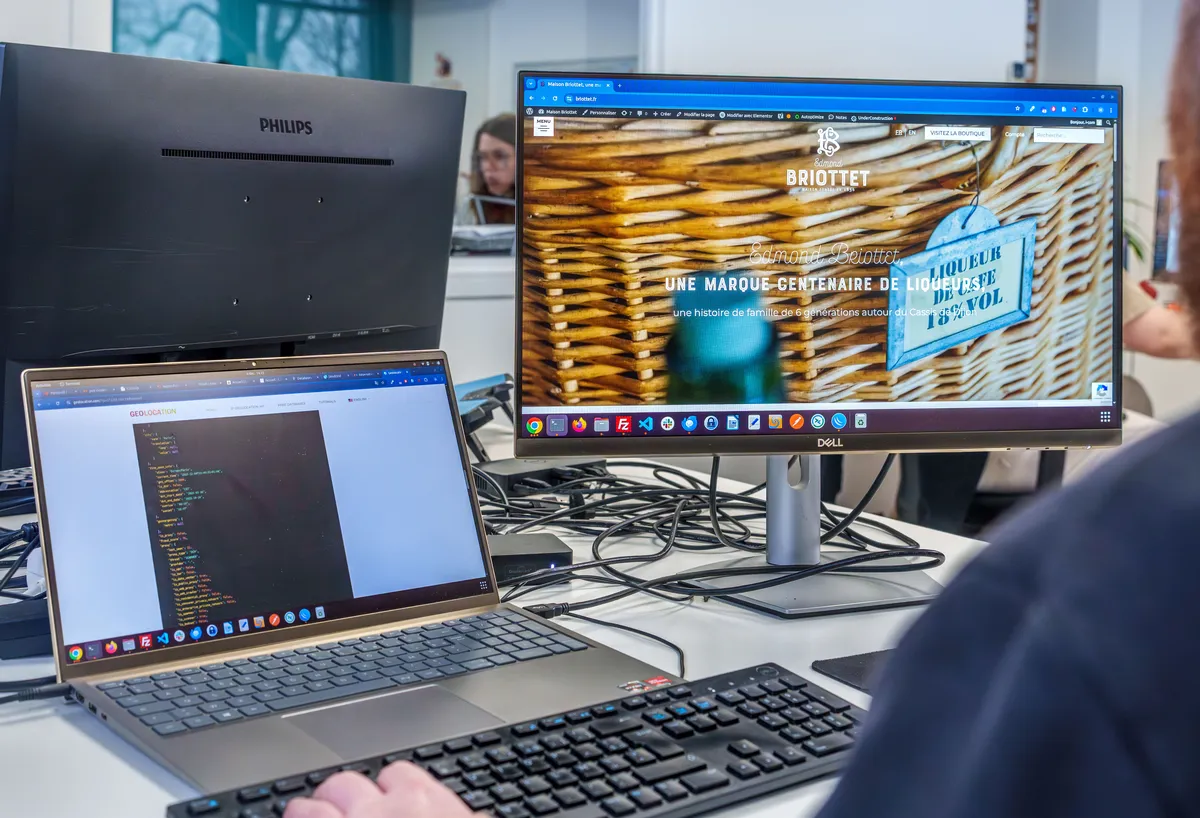 Poste de travail d'un développeur EcloLINK avec du code sur un laptop et l'aperçu d'un site internet client à l'écran