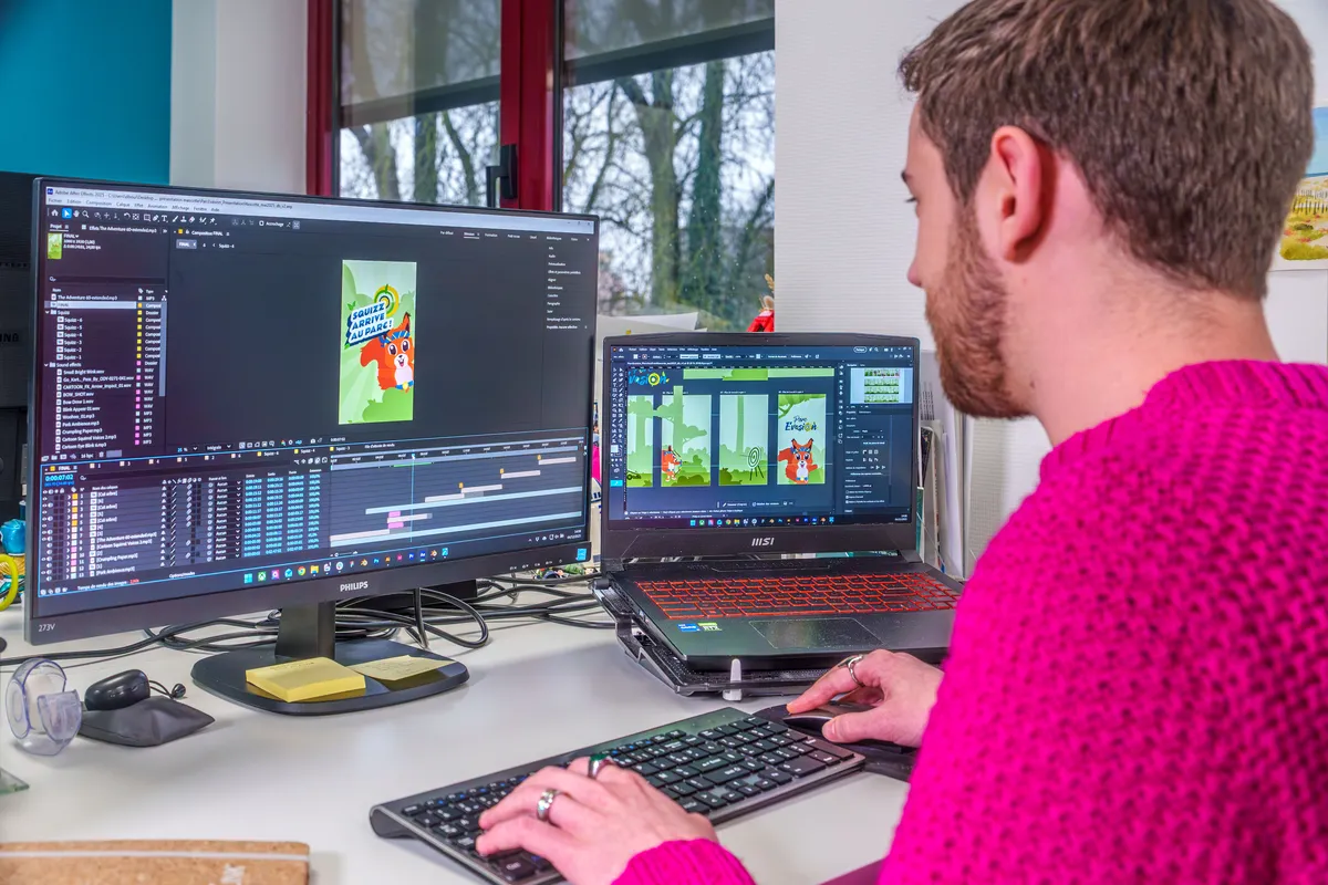 Motion designer travaillant sur une animation graphique dans After Effects avec éléments vectoriels sur écran secondaire.