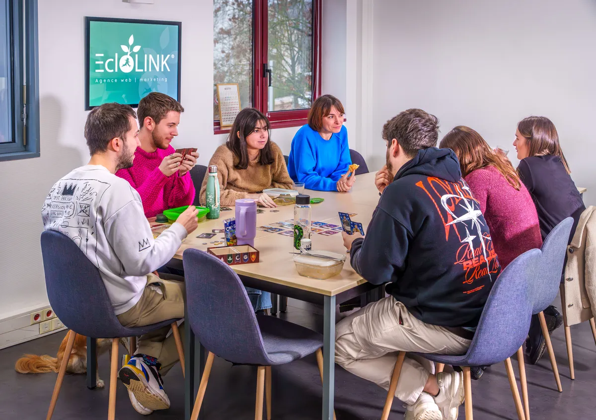 Équipe réunie autour d’une table pour une pause conviviale avec cartes et encas.