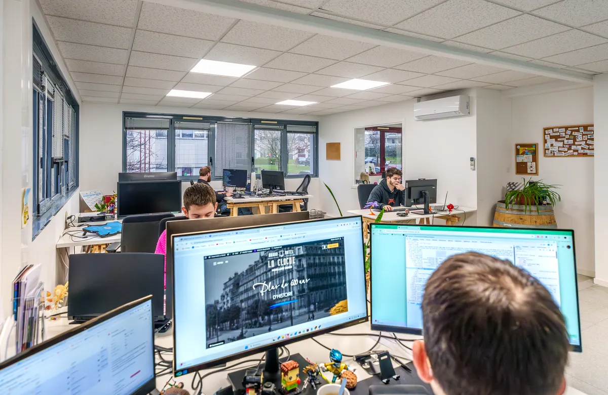 Espace de travail EcloLINK avec le site d'un hôtel client affiché à l'écran et l'équipe de développement en activité