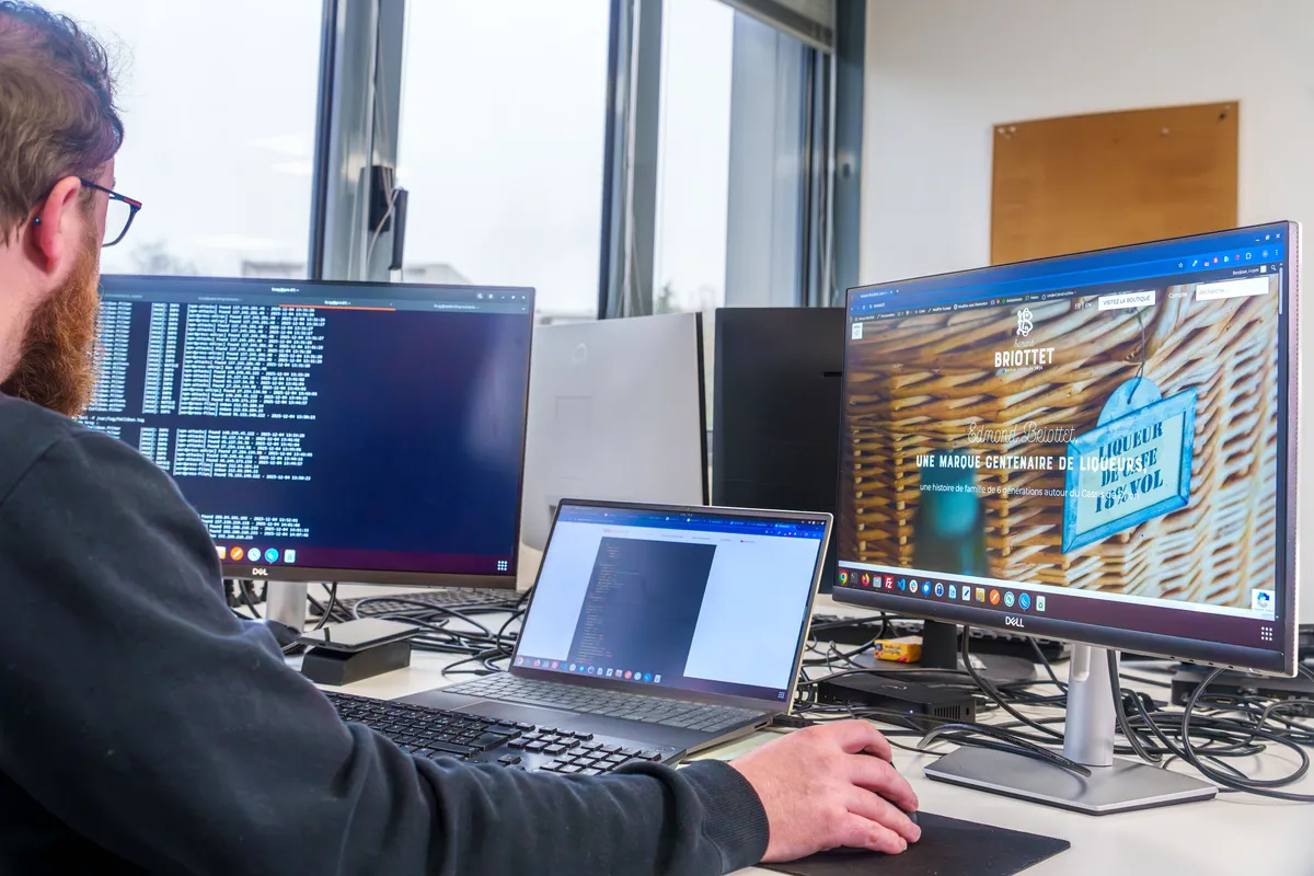Développeur EcloLINK travaillant sur un site client avec un terminal de code et un aperçu du site web sur plusieurs écrans