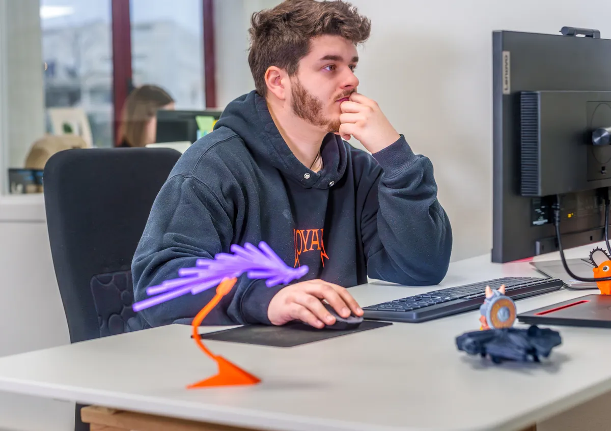 Développeur réfléchissant devant son écran d’ordinateur à son poste de travail.