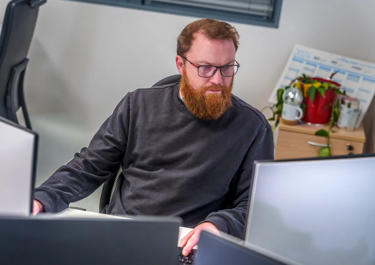 Développeur web senior de l'agence EcloLINK concentré devant ses écrans dans les bureaux de l'agence